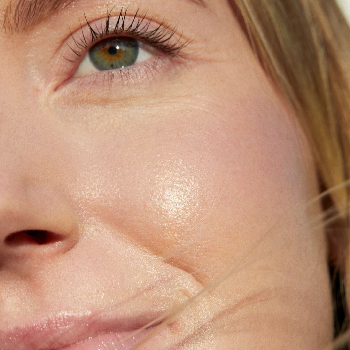 Nahaufnahme des Gesichts einer Person, fokussiert auf das Auge und die Hautstruktur.