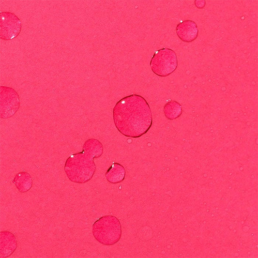 Wassertropfen auf einer ebenen pinkfarbenen Oberfläche.