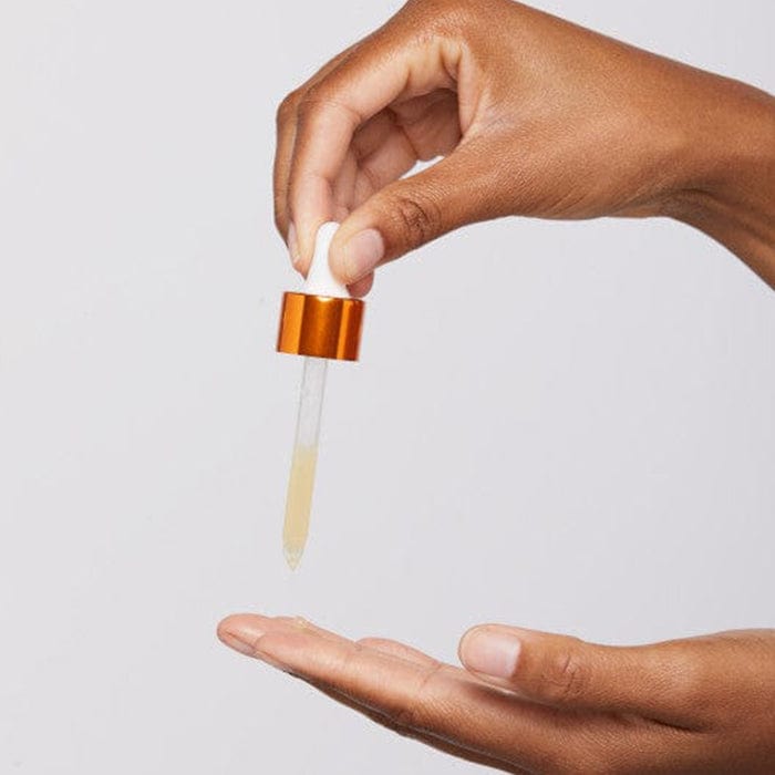 Die Hand einer Person hält eine kleine Flasche Brightening Biolumin-C Trio | Vitamin C Pflegeset mit zwei Gratis-Produkten.