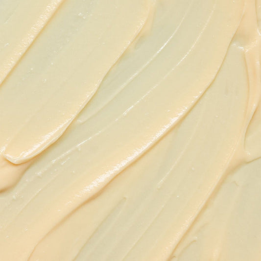 Nahaufnahme einer glatten, cremigen, hellgelben Substanz, die in strukturierten Wirbeln verteilt ist und der luxuriösen MultiVitamin Power Recovery Masque ähnelt, die für ihre antioxidative und Anti-Aging-Wirkung bekannt ist.