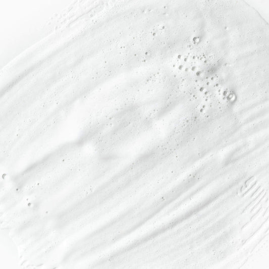 Textur einer weißen, schaumigen Flüssigkeit mit Luftblasen.