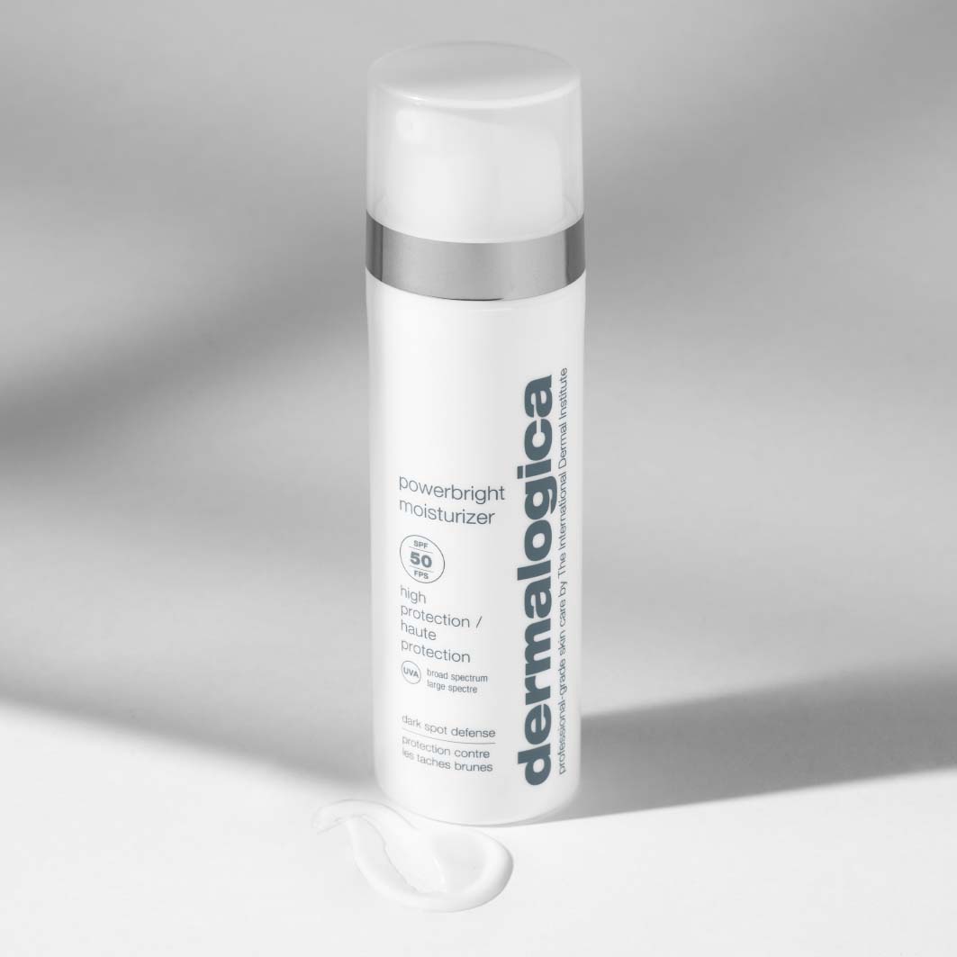 Flasche Powerbright Moisturizer mit SPF 50 auf hellem Hintergrund, eine kleine Menge des Produkts ist vor der Flasche ausgelaufen.