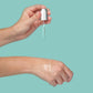 Hand hält Pipette über Handgelenk mit Hautpflegeprodukt-Tropfen.
