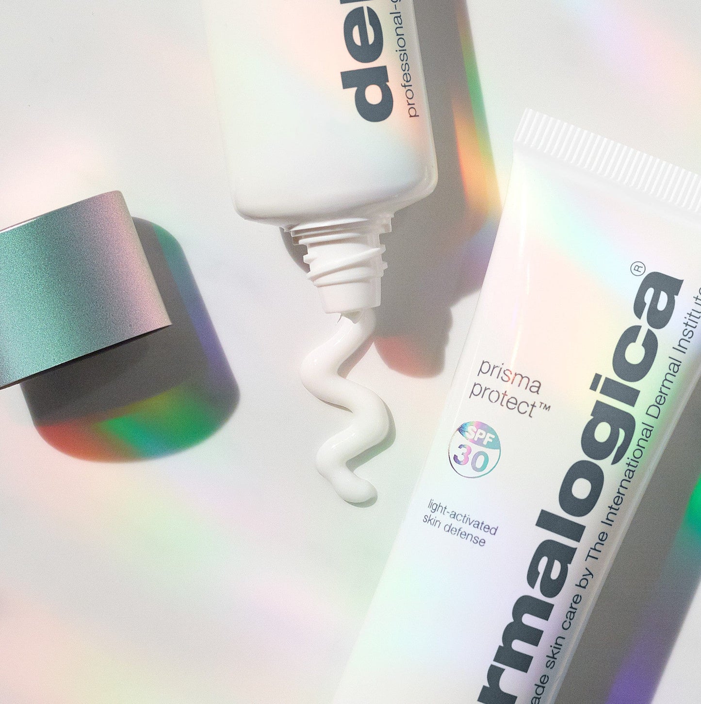 Hautpflegeprodukte mit Prisma Protect SPF 30 und geöffneter Tube, aus der eine Creme quillt, auf schimmerndem Hintergrund.