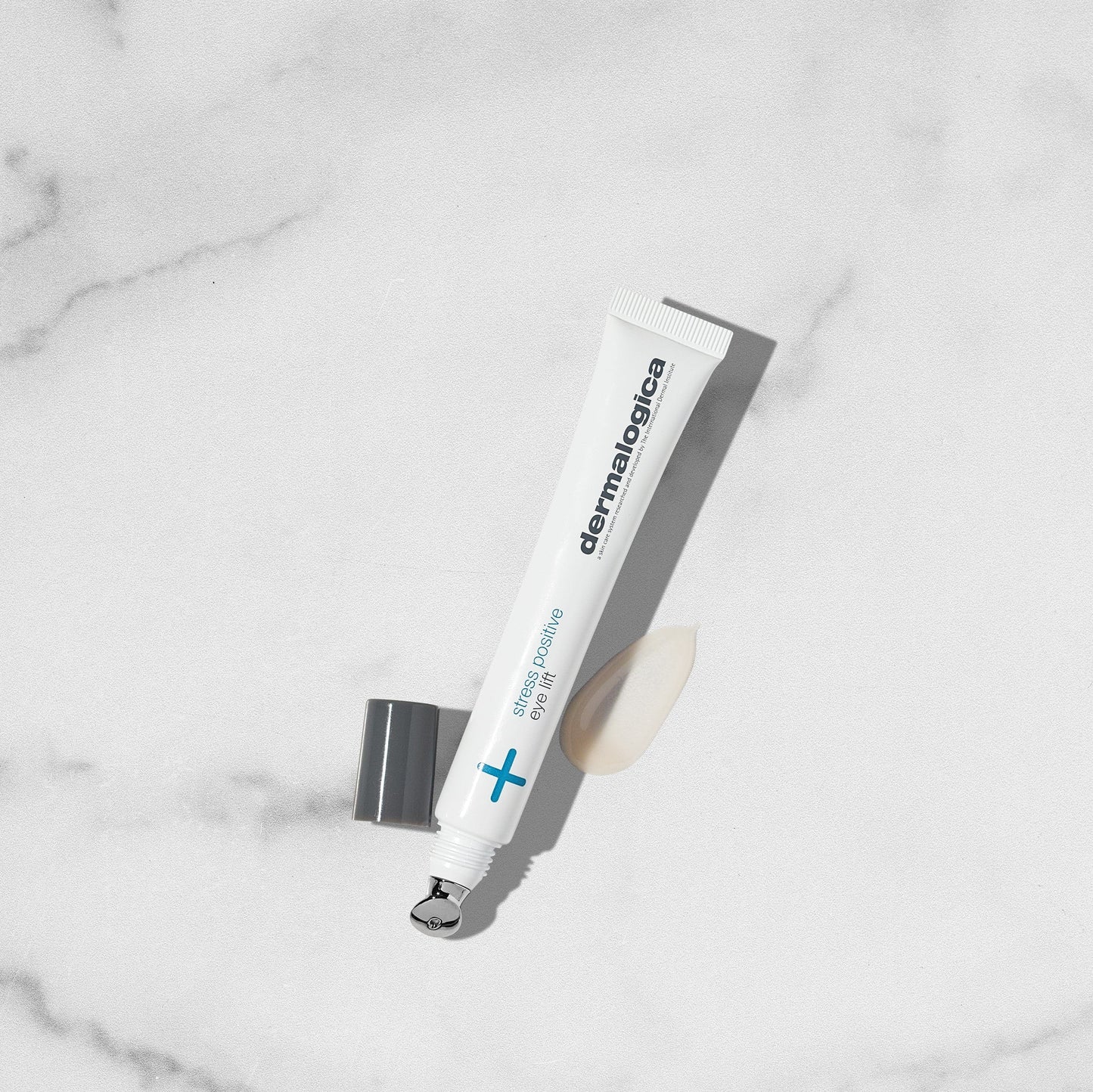 Tube von "Dermalogica Stress Positive Eye Lift" liegt auf marmorierter Oberfläche mit sichtbarem Produkt neben der geöffneten Kappe.