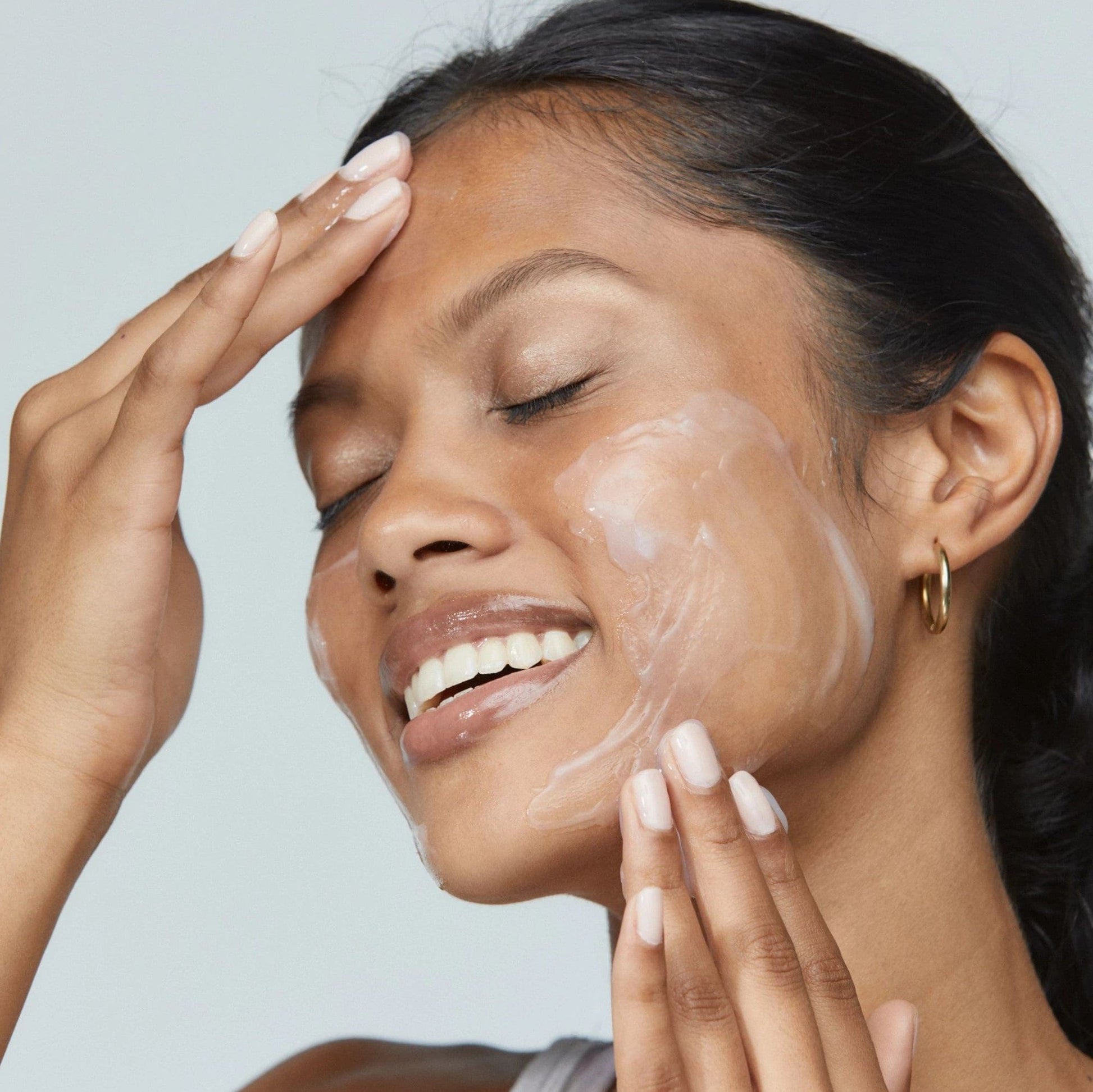 Frau wendet ein Hautpflegeprodukt auf ihrem Gesicht an.