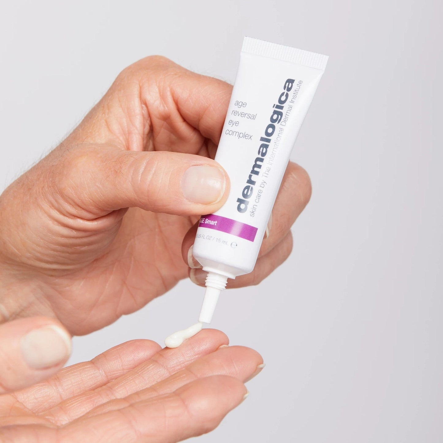 Eine Hand drückt eine kleine Menge Dermalogica Age Reversal Eye Complex Creme auf die Fingerspitzen.