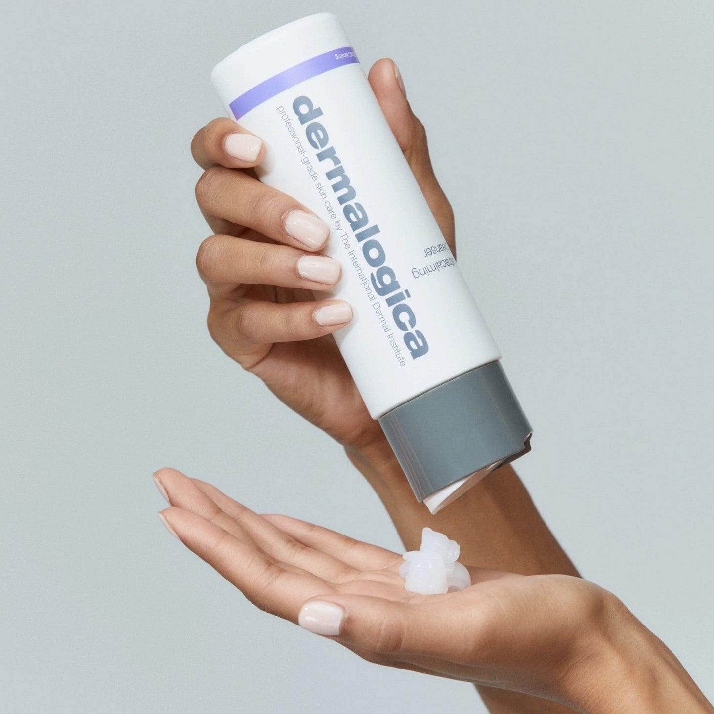 Hand hält Dermalogica-Flasche und dosiert Produkt auf die andere Handfläche.