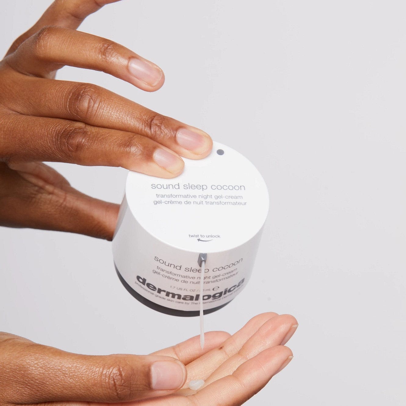 Eine Hand hält einen geöffneten Tiegel der Sound Sleep Cocoon Nachtcreme über der anderen Handfläche, wobei eine kleine Menge Produkt darauf ist.