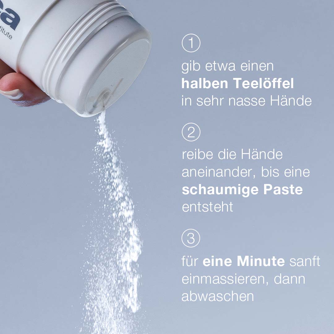 Eine Hand verteilt Daily Microfoliant aus einem Behälter mit deutscher Schritt-für-Schritt-Anleitung zur Herstellung einer schaumigen Paste zum Waschen der Hände und zur Verfeinerung des Hautbildes.