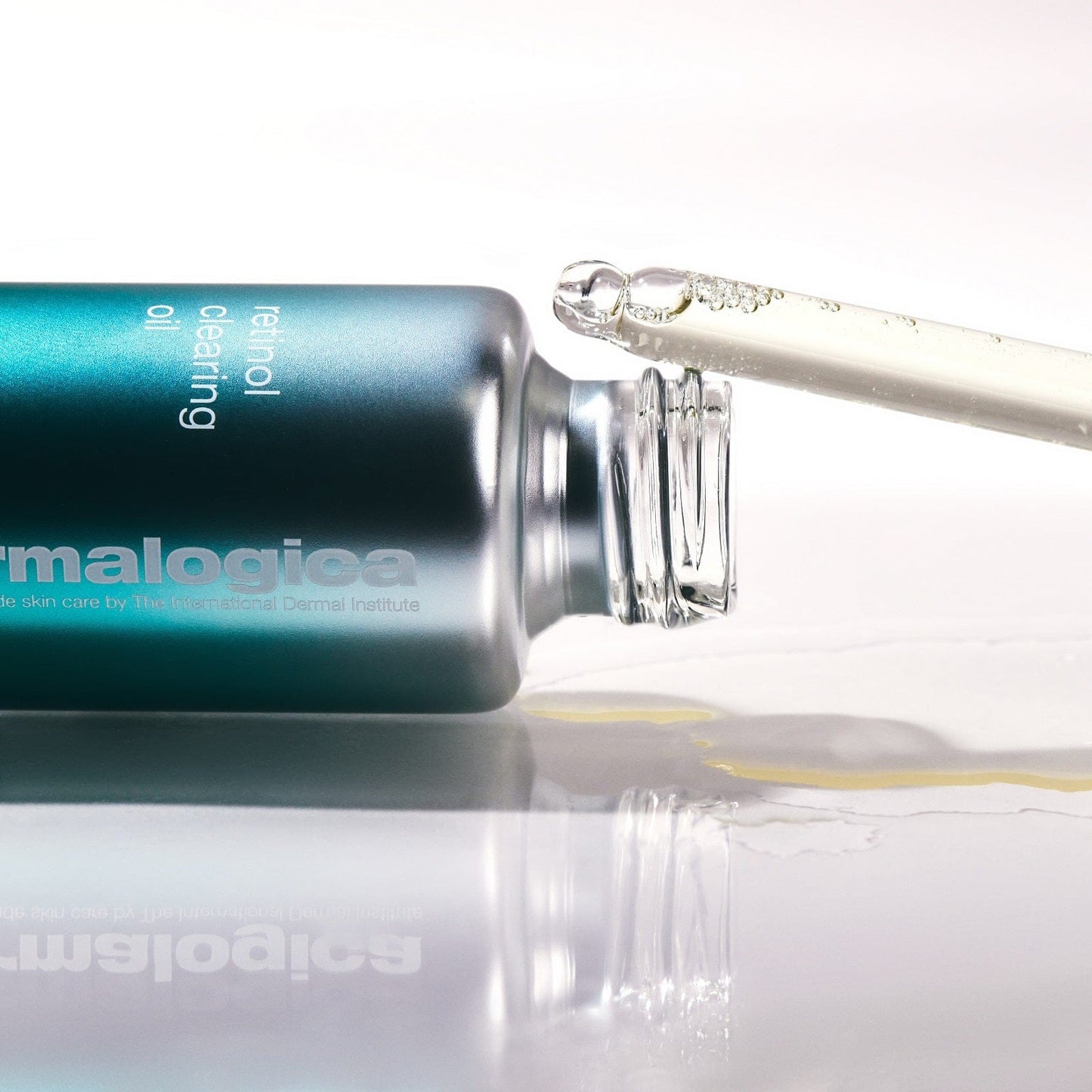 Eine Nahaufnahme der Dermalogica Retinol Clearing Oil Flasche, die perfekt für die Nachtpflege geeignet ist. Sie liegt auf der Seite, während ein offener Tropfer das mit Retinol und Salicylsäure angereicherte Öl ausgibt.