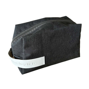 Eine rechteckige schwarze Dermalogica Reisetasche - gratis mit einer Reißverschlusstasche und weißem Griff mit geprägtem Text, dargestellt vor einem grauen Hintergrund.