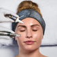 Eine Frau liegt mit geschlossenen Augen auf einer Behandlungsliege, während eine behandschuhte Hand mit dem Pro Pen Kit mit ExoBooster Serum aufträgt und Microneedling auf ihrer Wange durchführt.
