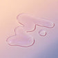 Klare Flüssigkeitströpfchen auf einer hellen Oberfläche mit einem Hintergrund mit sanftem Farbverlauf veranschaulichen die erfrischende Wirkung des Breakout Clearing Liquid Peel.