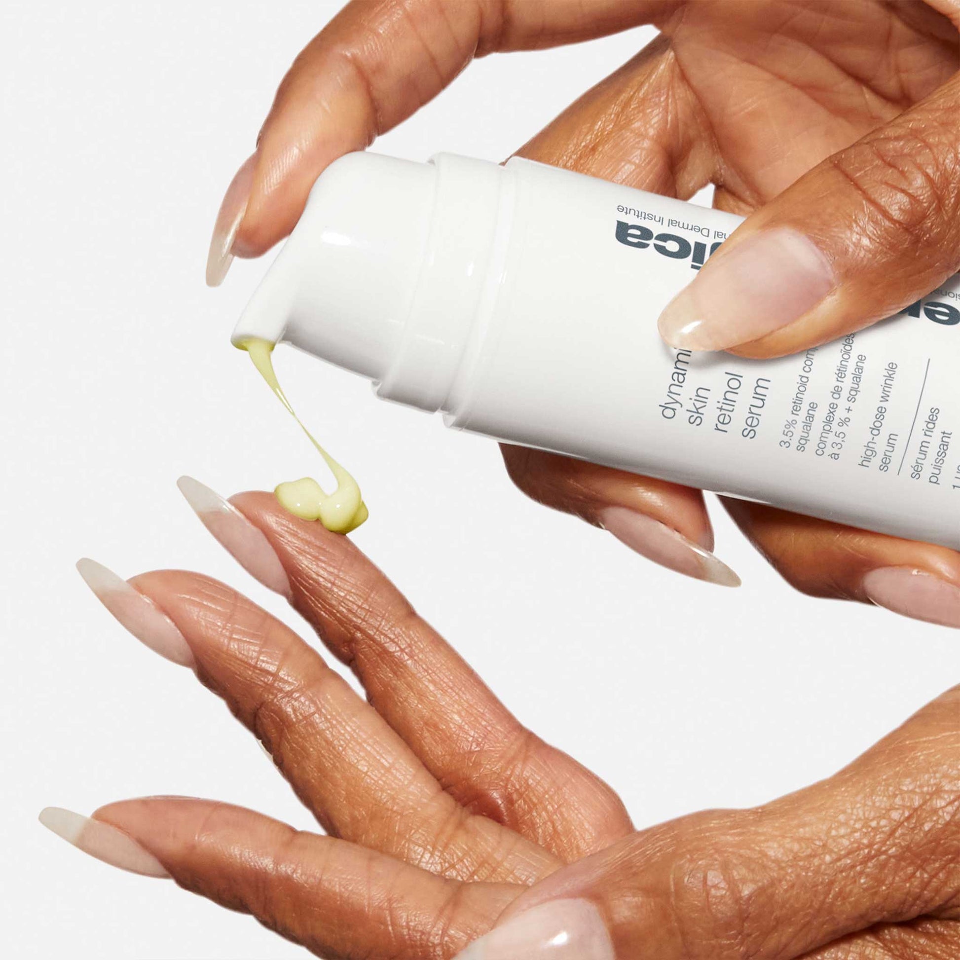 Eine Person gibt Dynamic Skin Retinol Serum aus einer weißen Flasche auf ihre Finger und bereitet sich darauf vor, das gelbliche Anti-Aging-Serum aufzutragen.