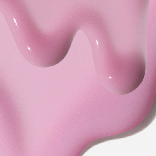 Glänzendes rosa Liquid Peelfoliant tropft und sammelt sich auf einer flachen Oberfläche, bildet sanfte Kurven und reflektiert Licht – und fängt so die sanfte, fließende Bewegung des Produkts ein.