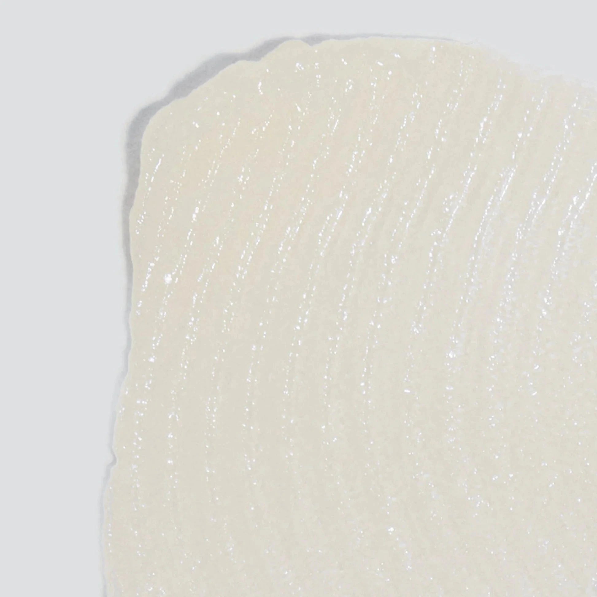 Nahaufnahme einer strukturierten, durchscheinend weißen Oberfläche mit geschwungenen Linien, die an Renewal Lip Complex 1,7 ml | Lippenpflege erinnert, angereichert mit Hyaluronsäure zur wohltuenden Pflege.