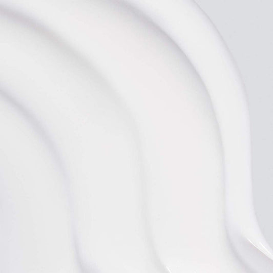 Nahaufnahme des glatten, weißen, cremigen Skin Resurfacing Cleansers mit geschwungenen Texturen auf hellem Hintergrund, angereichert mit antioxidativem Vitamin E und pflegendem Rosenöl.