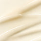 Geschmeidige, wellenartige Textur eines Hautpflegeprodukts in sanften Creme- und Weißtönen.