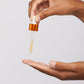 Hand mit Pipette träufelt klare Flüssigkeit auf die andere Hand 