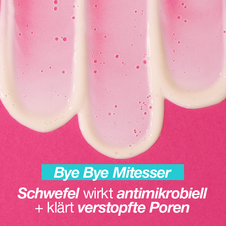 Drei Streifen einer pinkfarbenen Creme auf einem fuchsiafarbenen Hintergrund. Text im Bild: "Bye Bye Mitesser - Schwefel wirkt antimikrobiell + klärt verstopfte Poren".