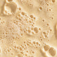 Eine Nahaufnahme eines Daily Milkfoliant | Puder-Peeling mit Blasen, die die Textur hervorheben.