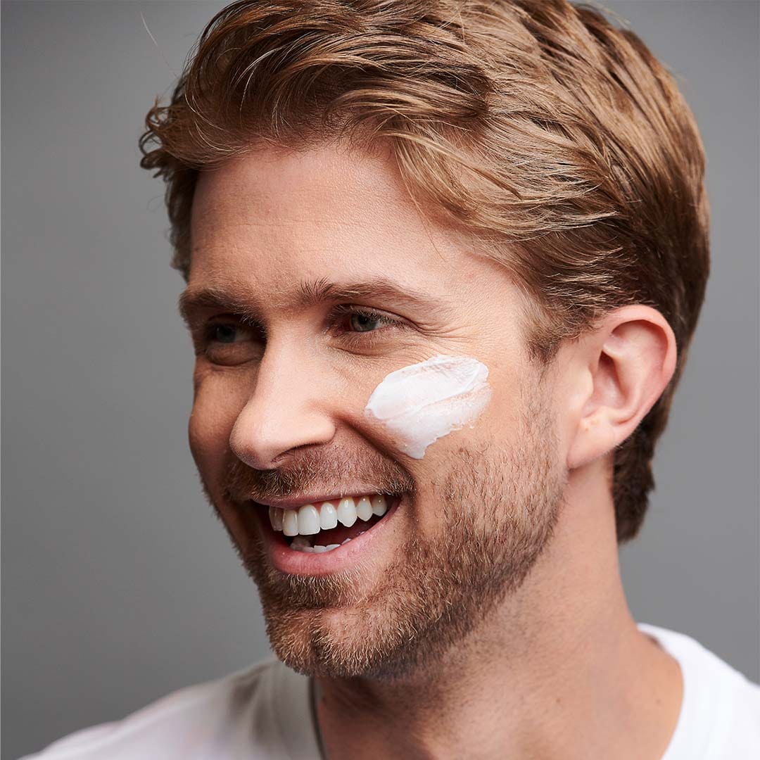 Ein lächelnder Mann mit einer PowerBright Feuchtigkeitscreme LSF50 50 ml | Pigmentausgleichende Feuchtigkeitspflege im Gesicht.