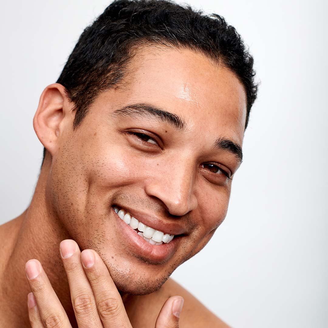 Ein Mann lächelt mit gereizter Haut und Rötungen im Gesicht und verwendet Calm Water Gel | Feuchtigkeitspflege.