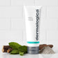 Tube der Dermalogica Sebum Clearing Masque mit Minzblättern und einer Holzröhre daneben auf einem weißen Hintergrund.