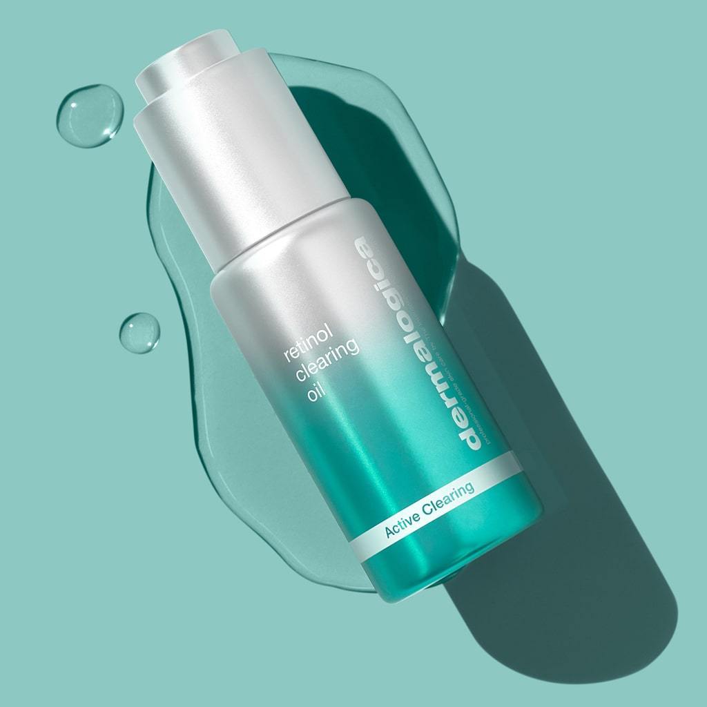 Flasche Retinol Clearing Oil vor einem hellgrünen Hintergrund mit Schattenwurf und einigen Tropfen neben der Verpackung.