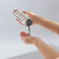 Die Hand einer Frau hält eine Flasche Daily Superfoliant | Puder-Peeling mit dreifach entgiftender Wirkung.