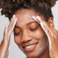 Eine Frau trägt eine Gesichtsmaske auf ihr Gesicht auf, um mithilfe von Daily Microfoliant den Teint ihrer Haut zu verbessern und abgestorbene Hautschüppchen wie Hautschüppchen zu entfernen.