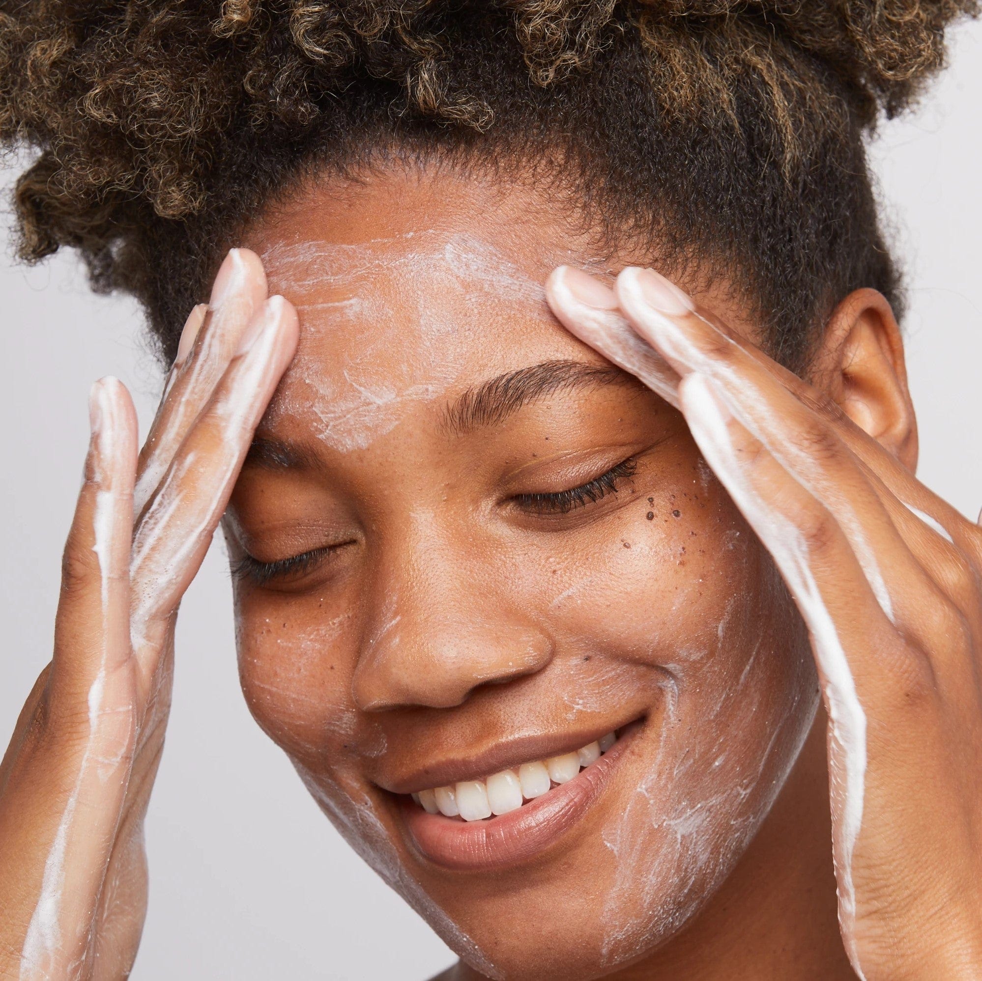 Eine Frau trägt eine Gesichtsmaske auf ihr Gesicht auf, um mithilfe von Daily Microfoliant den Teint ihrer Haut zu verbessern und abgestorbene Hautschüppchen wie Hautschüppchen zu entfernen.