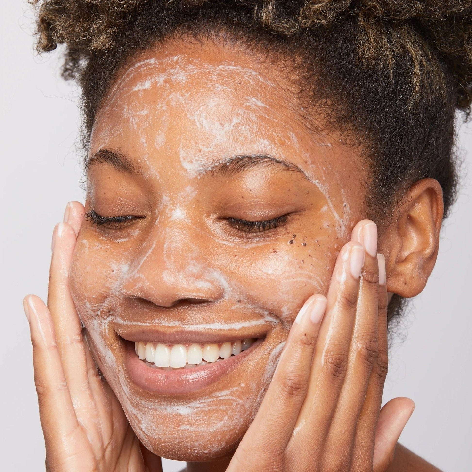 Eine Frau, die eine Gesichtsmaske trägt und das spezielle Reinigungsgel verwendet, um Schmutz und Unreinheiten von ihrer Haut zu entfernen.