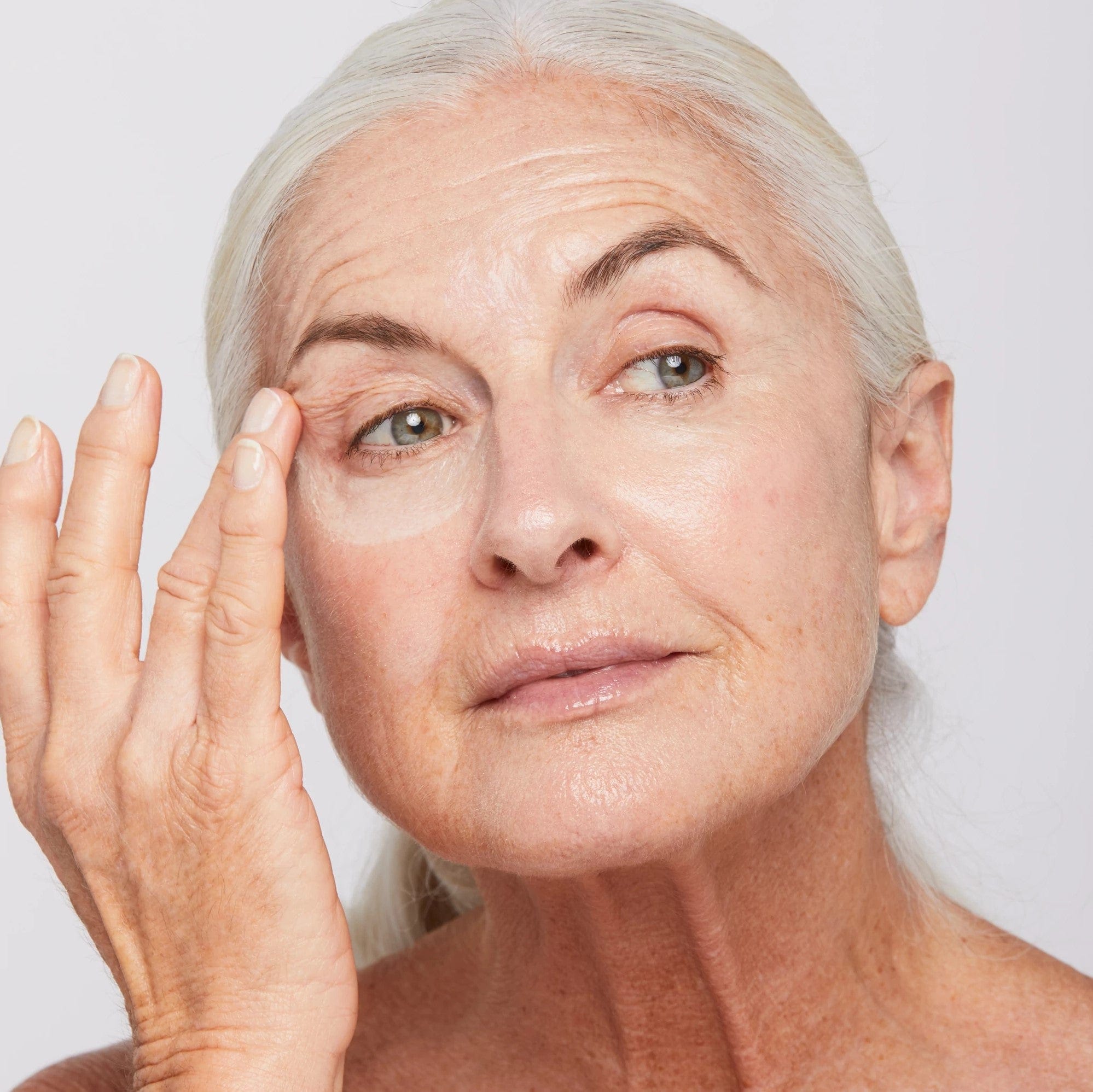 Eine Frau trägt AGE Reversal Eye Complex 15 ml auf ihr Auge auf, um Augenringe zu reduzieren und das Erscheinungsbild von Linien und Falten zu verbessern.