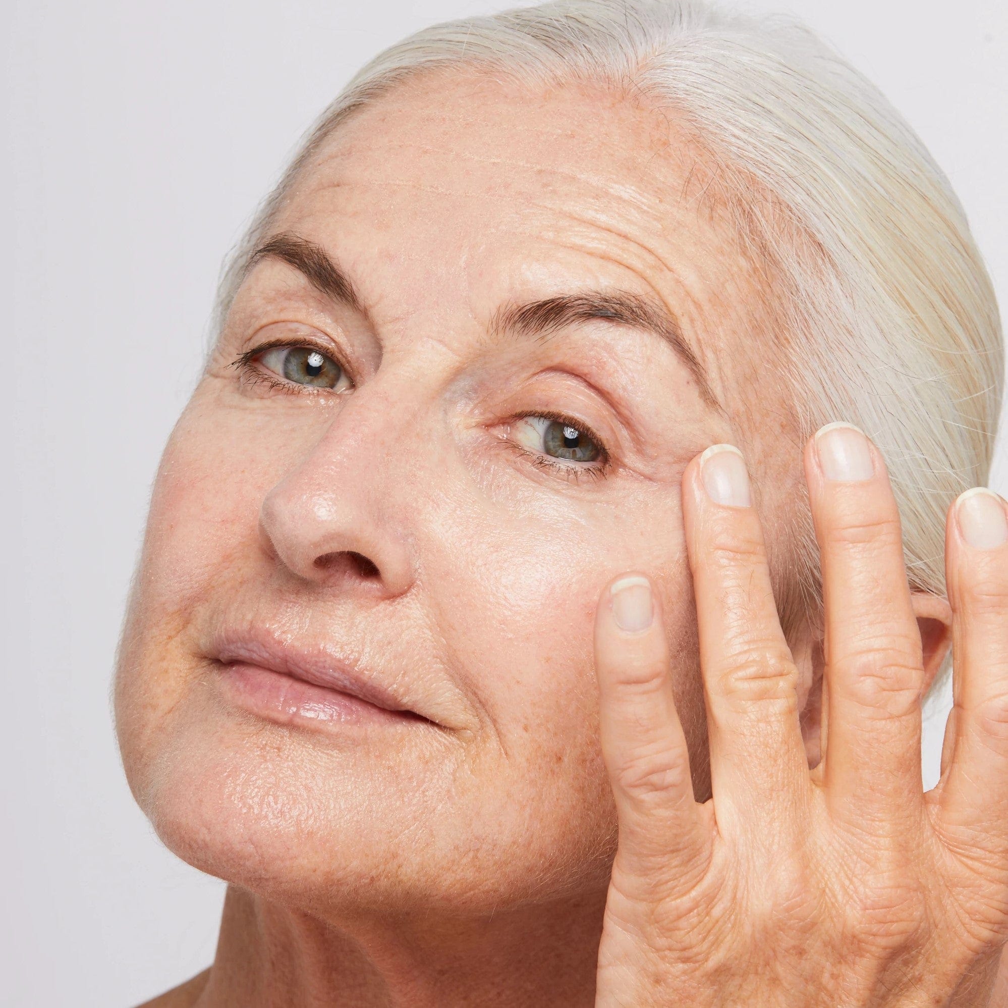 Eine Frau legt ihre Hand auf ihr Gesicht und trägt MultiVitamin Power Firm 15 ml | auf Augencreme zur Reduzierung von Falten.