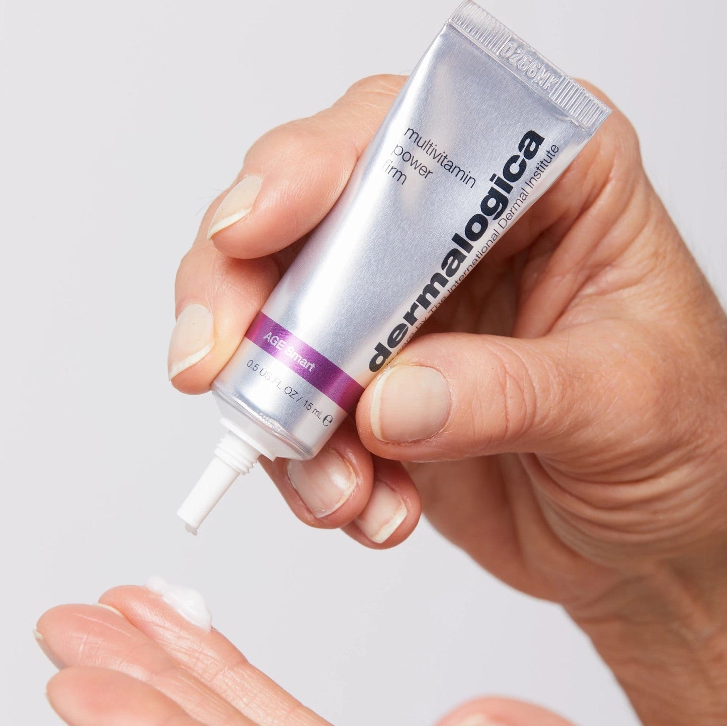 Eine Person, die eine Tube MultiVitamin Power Firm 15 ml | aufträgt Augencreme mit Vitaminen und glättenden Eigenschaften für die Hand, gezielt zur Faltenreduzierung.