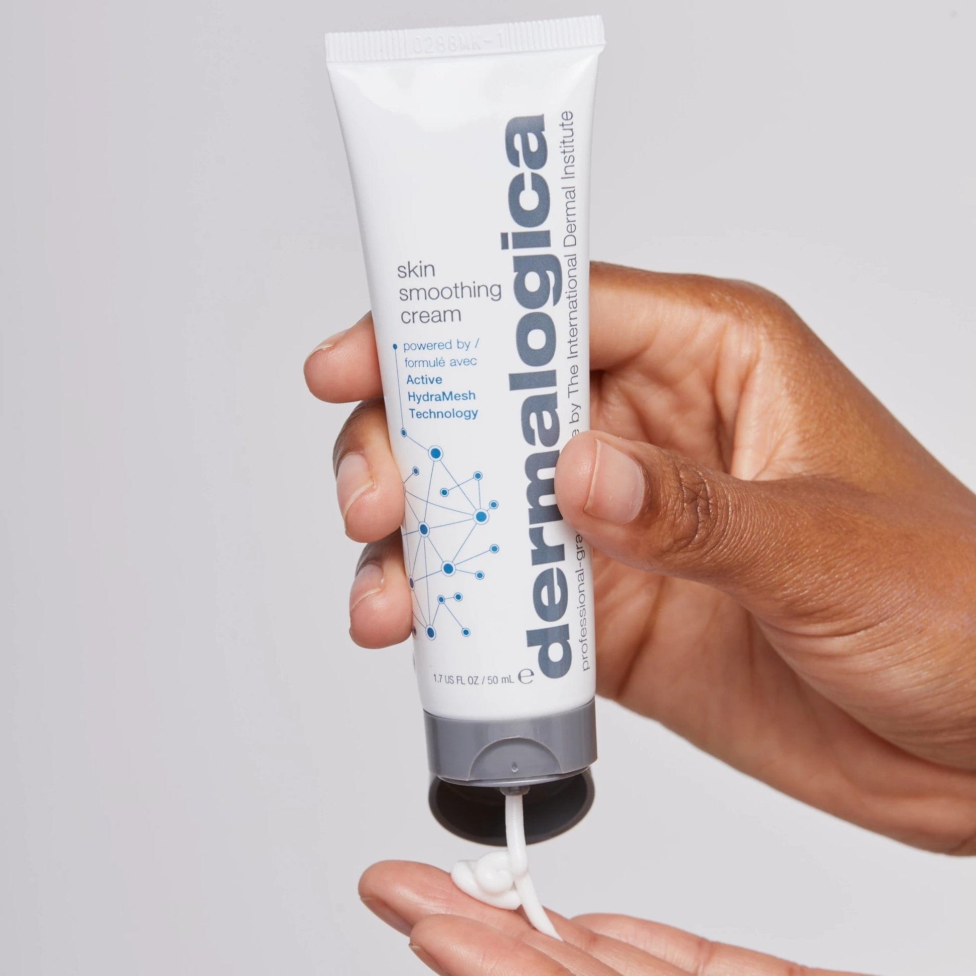 Eine Hand hält eine Tube Dermalogica Skin Smoothing Cream mit ausgedrücktem Produkt.