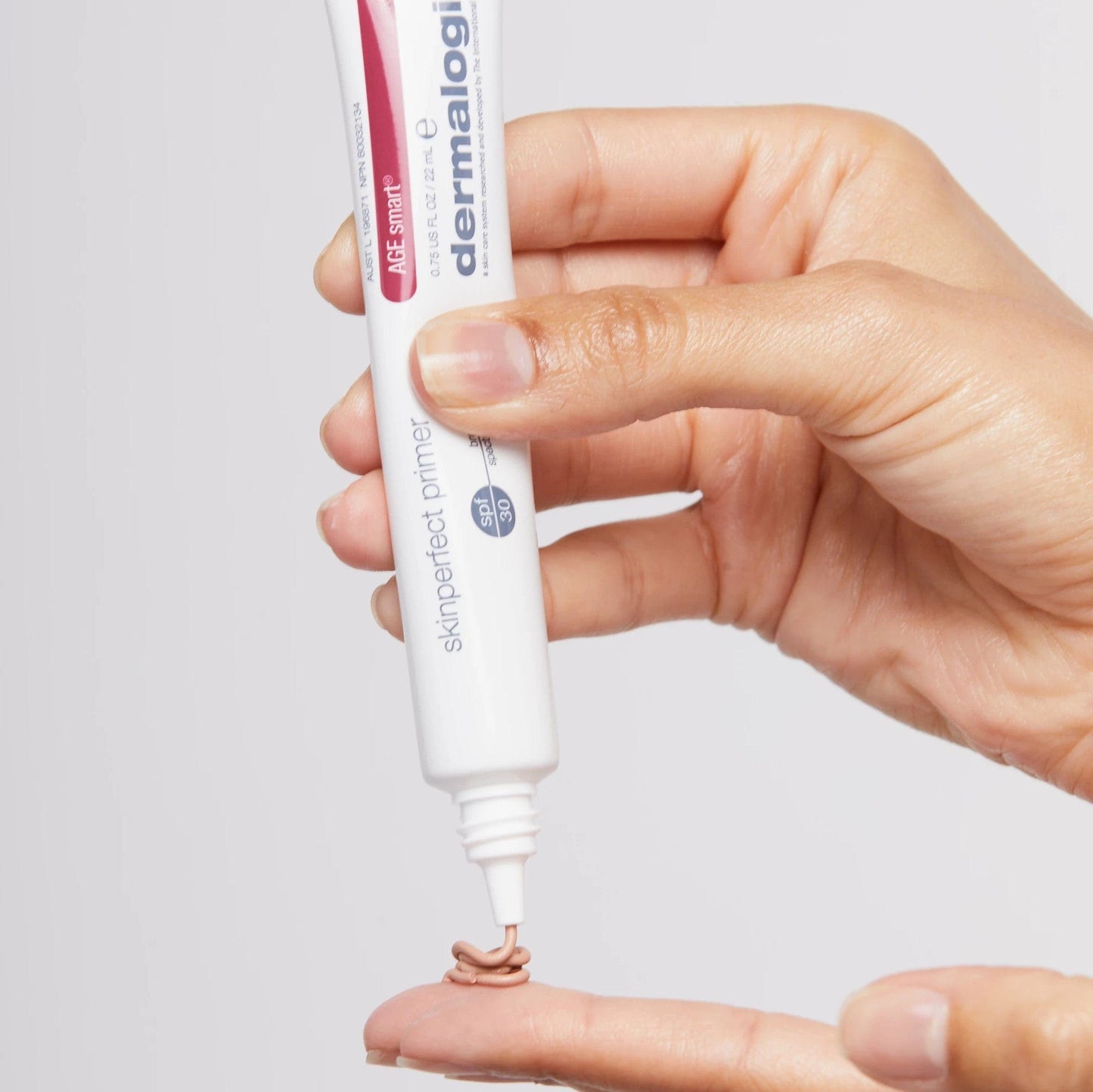 Hand hält eine Tube Skinperfect Primer, aus der eine kleine Menge des Produktes herausgedrückt wird.