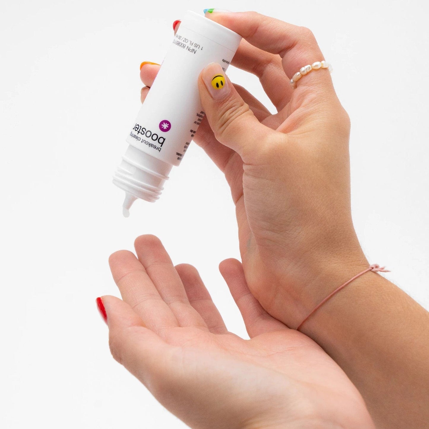 Die Hand einer Frau hält eine Flasche Augencreme mit Breakout Clearing Booster 30 ml | Booster bei unreiner Haut drauf.